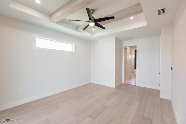 spare room with light wood-type flooring, a tray ceiling, and ceiling fan