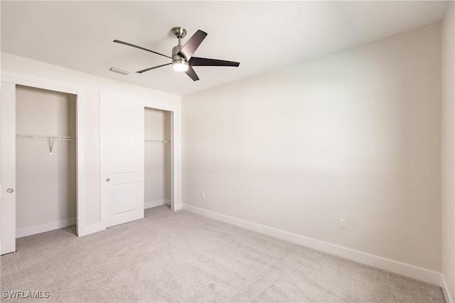 unfurnished bedroom with visible vents, baseboards, two closets, and light colored carpet