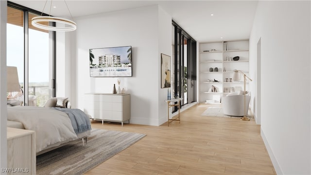 bedroom with expansive windows, light hardwood / wood-style flooring, and an inviting chandelier