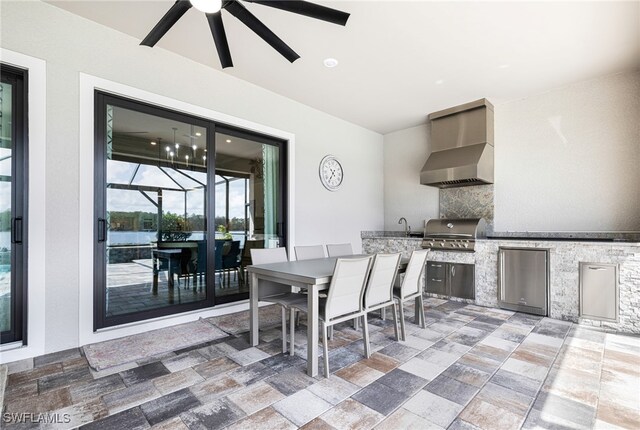 view of patio with a lanai, grilling area, ceiling fan, and exterior kitchen