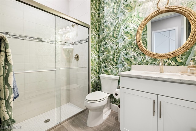 bathroom featuring hardwood / wood-style flooring, vanity, toilet, and a shower with door