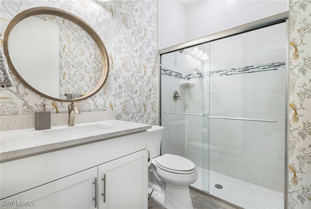 bathroom featuring a shower with door, vanity, hardwood / wood-style floors, and toilet