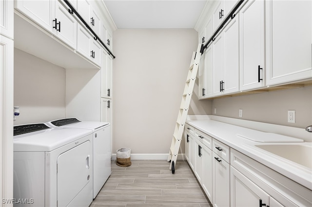 clothes washing area featuring washer and dryer, light hardwood / wood-style flooring, cabinets, and sink