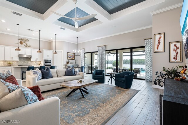 living room featuring ceiling fan with notable chandelier, coffered ceiling, and ornamental molding