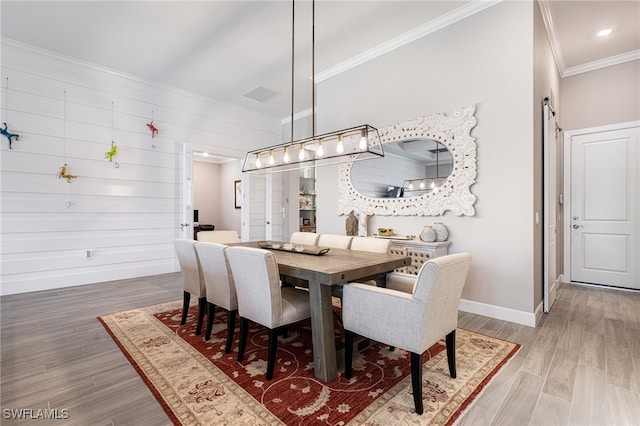 dining space with hardwood / wood-style floors, a barn door, and crown molding