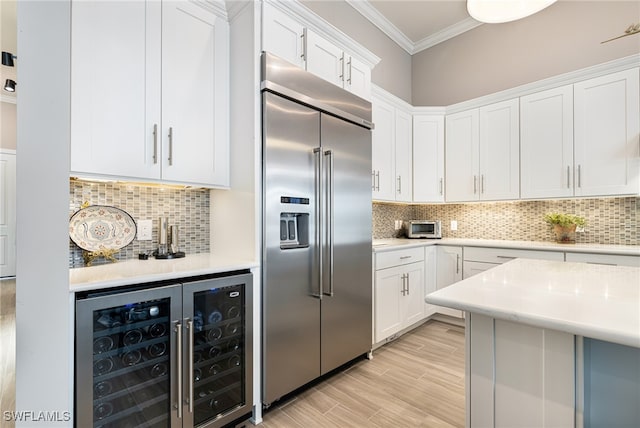 kitchen featuring white cabinets, decorative backsplash, beverage cooler, and built in fridge