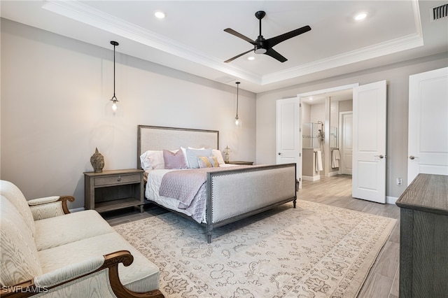 bedroom featuring light wood-type flooring, a tray ceiling, and ceiling fan