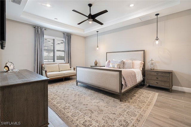 bedroom with ceiling fan, light hardwood / wood-style floors, a raised ceiling, and ornamental molding