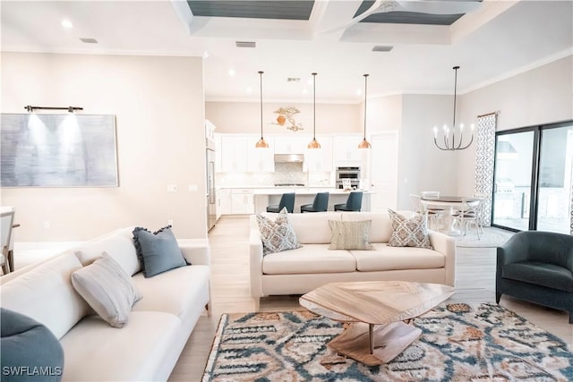 living room featuring an inviting chandelier, crown molding, and light wood-type flooring