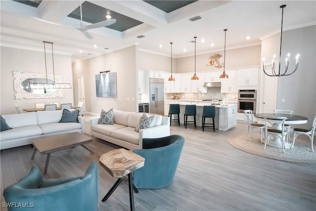 living room with ornamental molding, light hardwood / wood-style floors, a high ceiling, and coffered ceiling