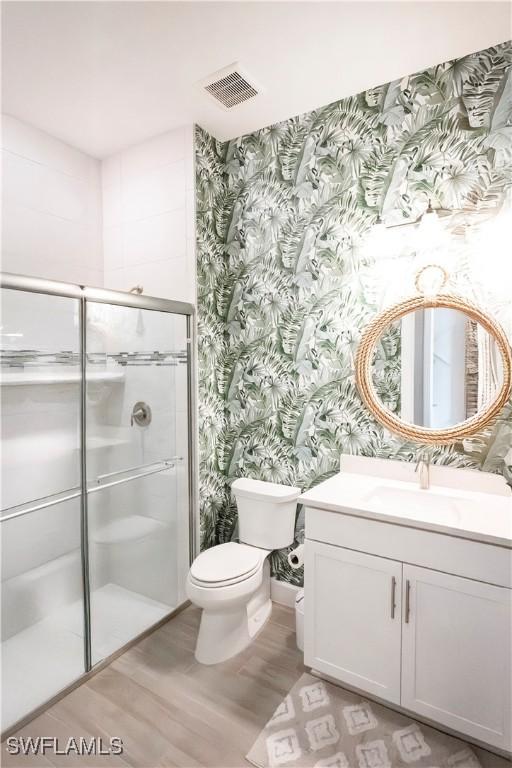 bathroom featuring toilet, hardwood / wood-style flooring, an enclosed shower, and vanity