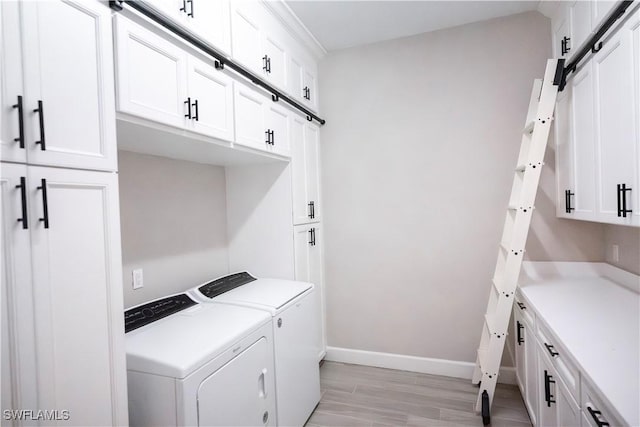 washroom featuring a barn door, separate washer and dryer, cabinets, and light hardwood / wood-style flooring