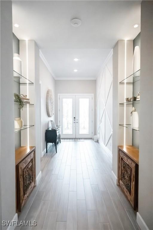 hall with ornamental molding, light wood-type flooring, and french doors