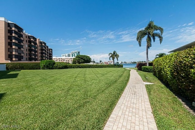 view of home's community with a water view and a lawn