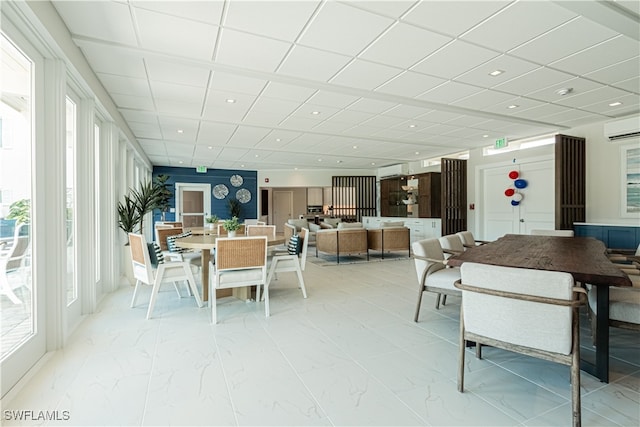 dining room with a wall unit AC and a drop ceiling