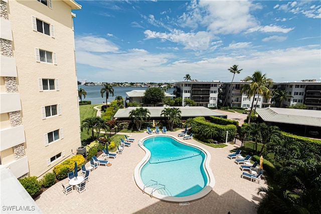 view of pool featuring a water view and a patio