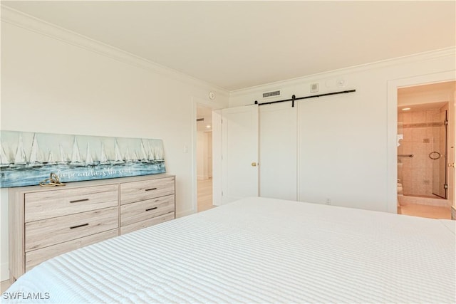 bedroom featuring connected bathroom, crown molding, and a barn door