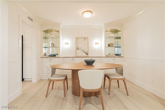 dining area featuring ornamental molding, light wood-type flooring, and breakfast area