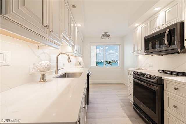 kitchen featuring appliances with stainless steel finishes, sink, backsplash, and light stone counters