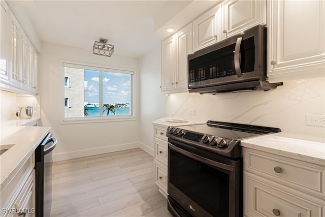 kitchen featuring stainless steel appliances, white cabinetry, and a water view