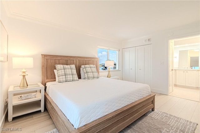 bedroom with ornamental molding, light hardwood / wood-style floors, and a closet