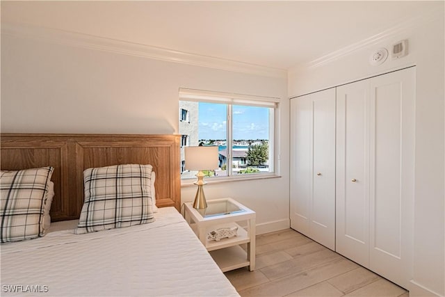 bedroom with crown molding, light hardwood / wood-style floors, and a closet