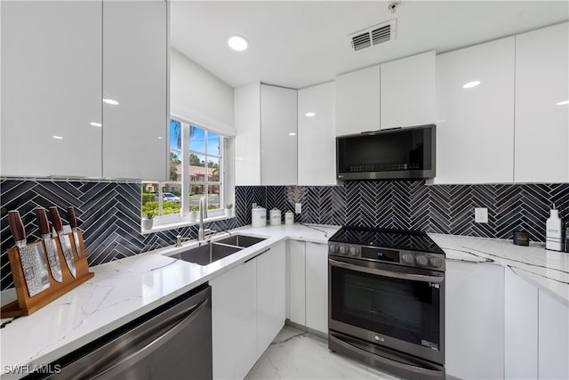 kitchen featuring backsplash, sink, appliances with stainless steel finishes, and white cabinetry