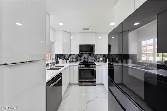 kitchen with appliances with stainless steel finishes, backsplash, white cabinetry, and sink