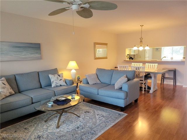 living room featuring dark wood-type flooring and ceiling fan with notable chandelier