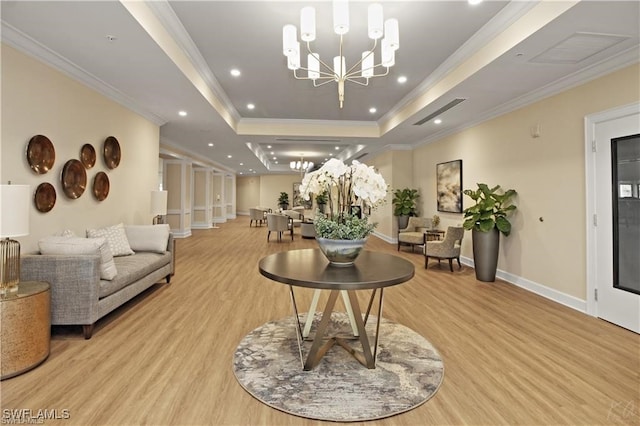 living room featuring crown molding, a raised ceiling, light hardwood / wood-style flooring, and a chandelier