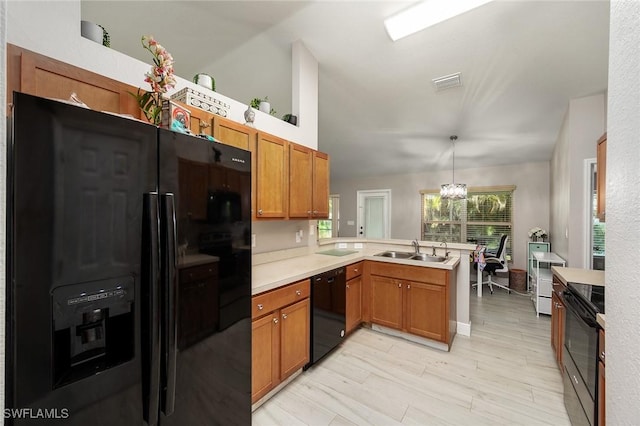 kitchen featuring kitchen peninsula, sink, black appliances, pendant lighting, and a chandelier