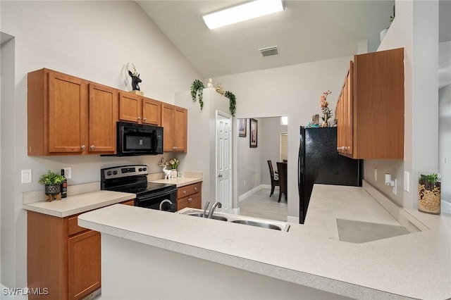 kitchen featuring black appliances, lofted ceiling, kitchen peninsula, and sink