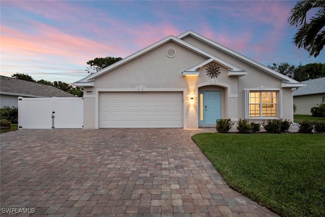 ranch-style house with a garage and a lawn