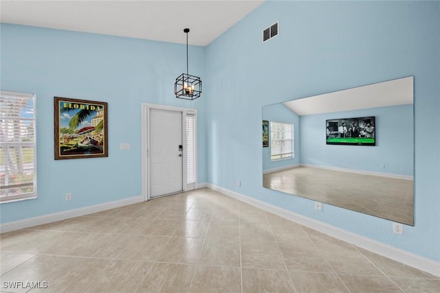 entrance foyer featuring a chandelier, vaulted ceiling, and light tile patterned floors