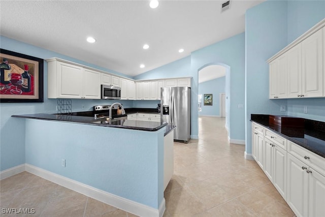 kitchen featuring lofted ceiling, sink, appliances with stainless steel finishes, white cabinetry, and kitchen peninsula