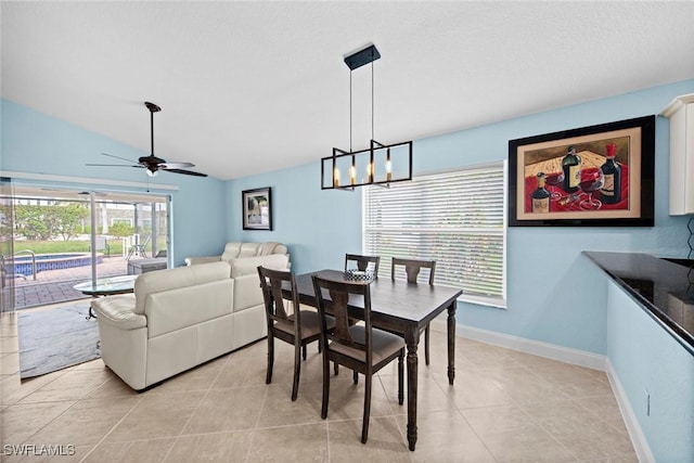 dining room with ceiling fan with notable chandelier, vaulted ceiling, and light tile patterned floors