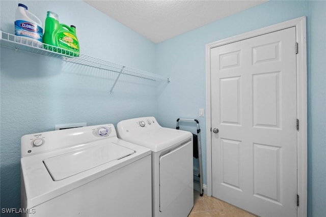 laundry room featuring washer and clothes dryer, a textured ceiling, and light tile patterned floors