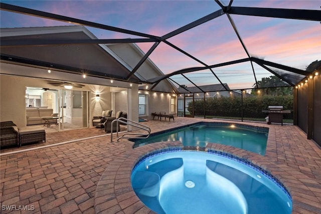 pool at dusk with an in ground hot tub, a lanai, area for grilling, and a patio area