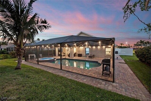 pool at dusk featuring an in ground hot tub, a grill, a yard, and a patio