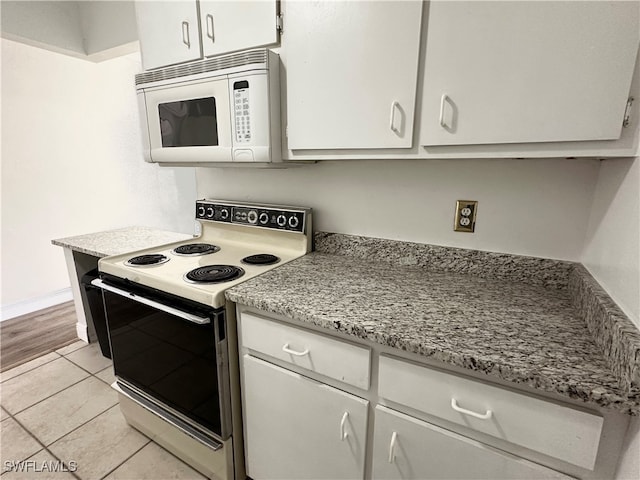 kitchen with range with electric cooktop, light tile patterned floors, and white cabinets