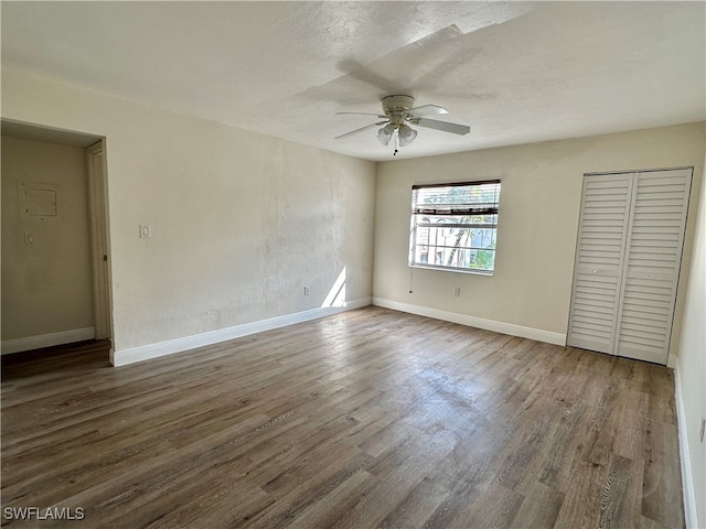 unfurnished bedroom featuring ceiling fan, a textured ceiling, dark hardwood / wood-style flooring, and a closet