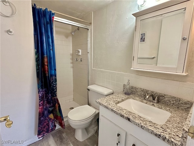 bathroom featuring tile walls, hardwood / wood-style floors, vanity, curtained shower, and toilet