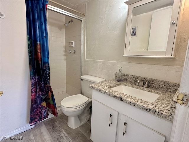 bathroom with tile walls, hardwood / wood-style floors, vanity, curtained shower, and toilet