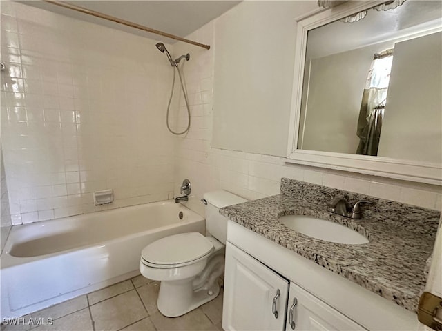 full bathroom with tile patterned floors, toilet, tiled shower / bath, tile walls, and vanity