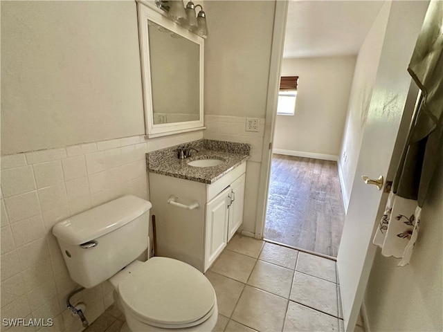 bathroom with vanity, toilet, tile patterned flooring, and tile walls