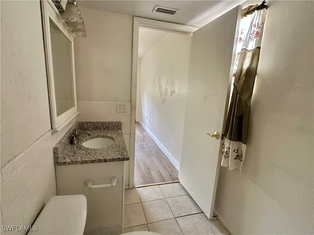 bathroom with vanity, tile walls, tile patterned floors, and toilet