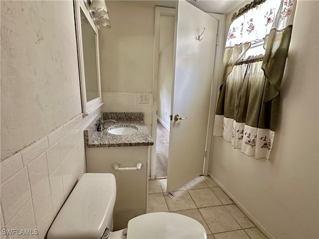 bathroom with tile walls, vanity, tile patterned flooring, and toilet