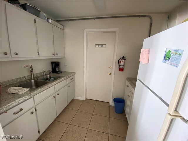 kitchen featuring light tile patterned floors, sink, white fridge, and white cabinets