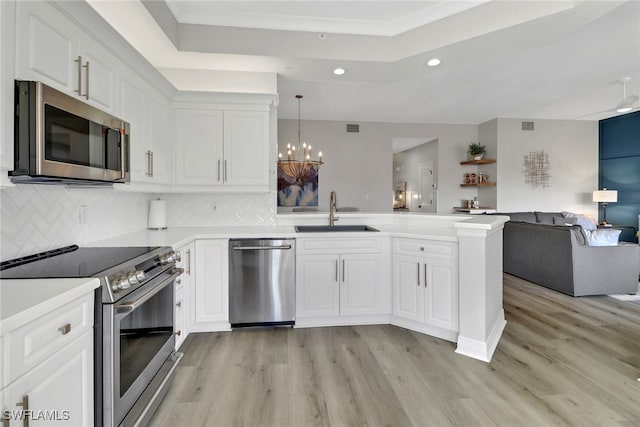 kitchen featuring light wood-type flooring, appliances with stainless steel finishes, sink, kitchen peninsula, and tasteful backsplash