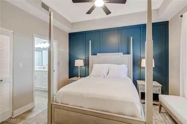 bedroom with light hardwood / wood-style flooring, ceiling fan, ensuite bathroom, and sink